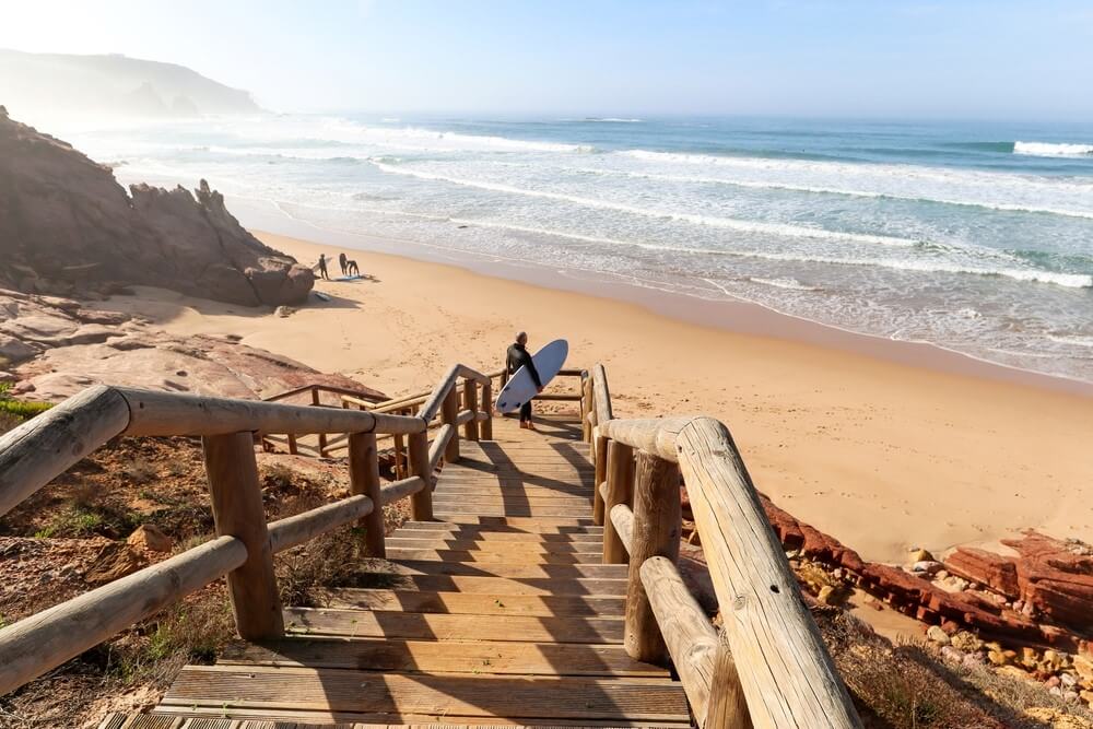 man standing with surf board near sea
