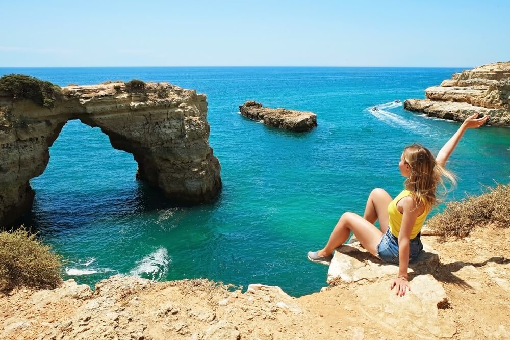 women sitting on the edge of seashore